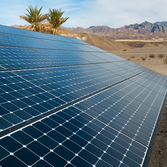 a row of solar panels in the desert with mountains in the background