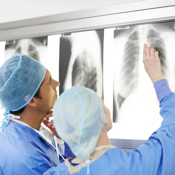 two surgeons are looking at an x-ray of a patient 's lungs